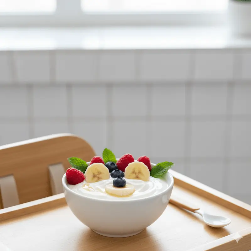 Best Healthy Snack Ideas for Toddlers Small bowl of creamy yogurt topped with fresh berries and banana slices, a colorful and healthy snack for toddlers in bright natural kitchen lighting